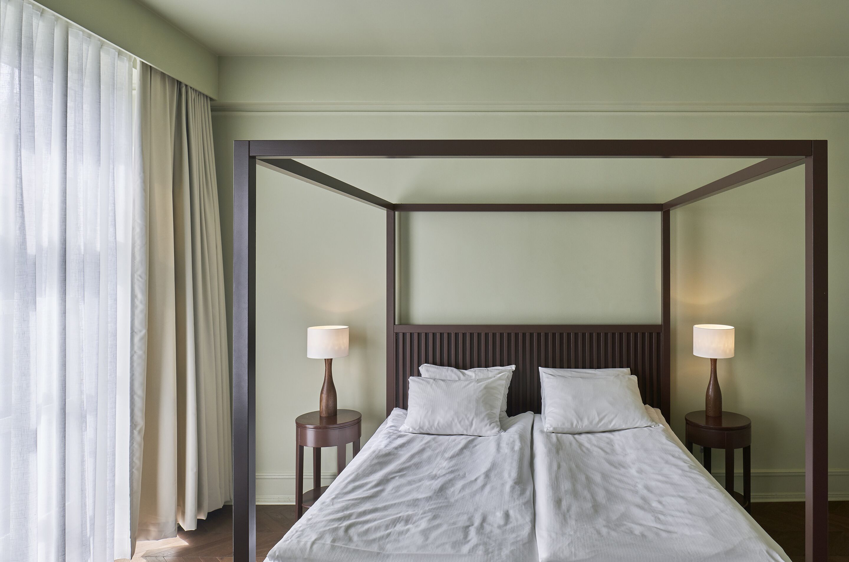 Habitación de hotel con una cama grande, dos mesitas de noche y un espejo grande sobre la cama.