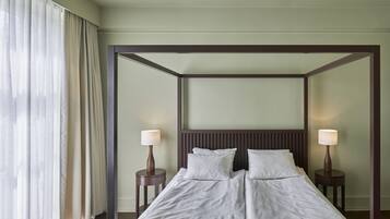 Habitación de hotel con una cama grande, dos mesitas de noche y un espejo grande sobre la cama.