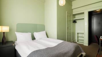 Una habitación de hotel con cama, mesita de noche, lámpara, armario y puerta.