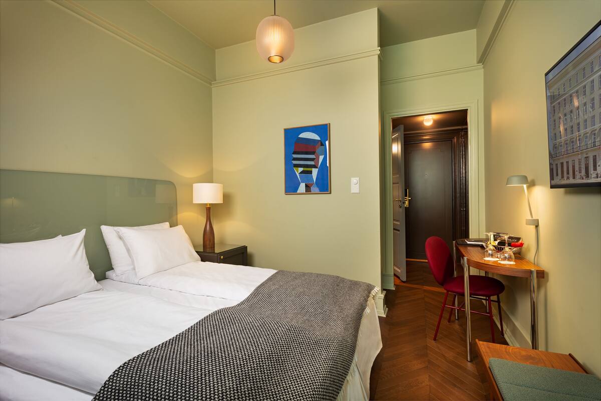 Ein Hotelzimmer mit Bett, Schreibtisch, Stuhl und einem Bild an der Wand.