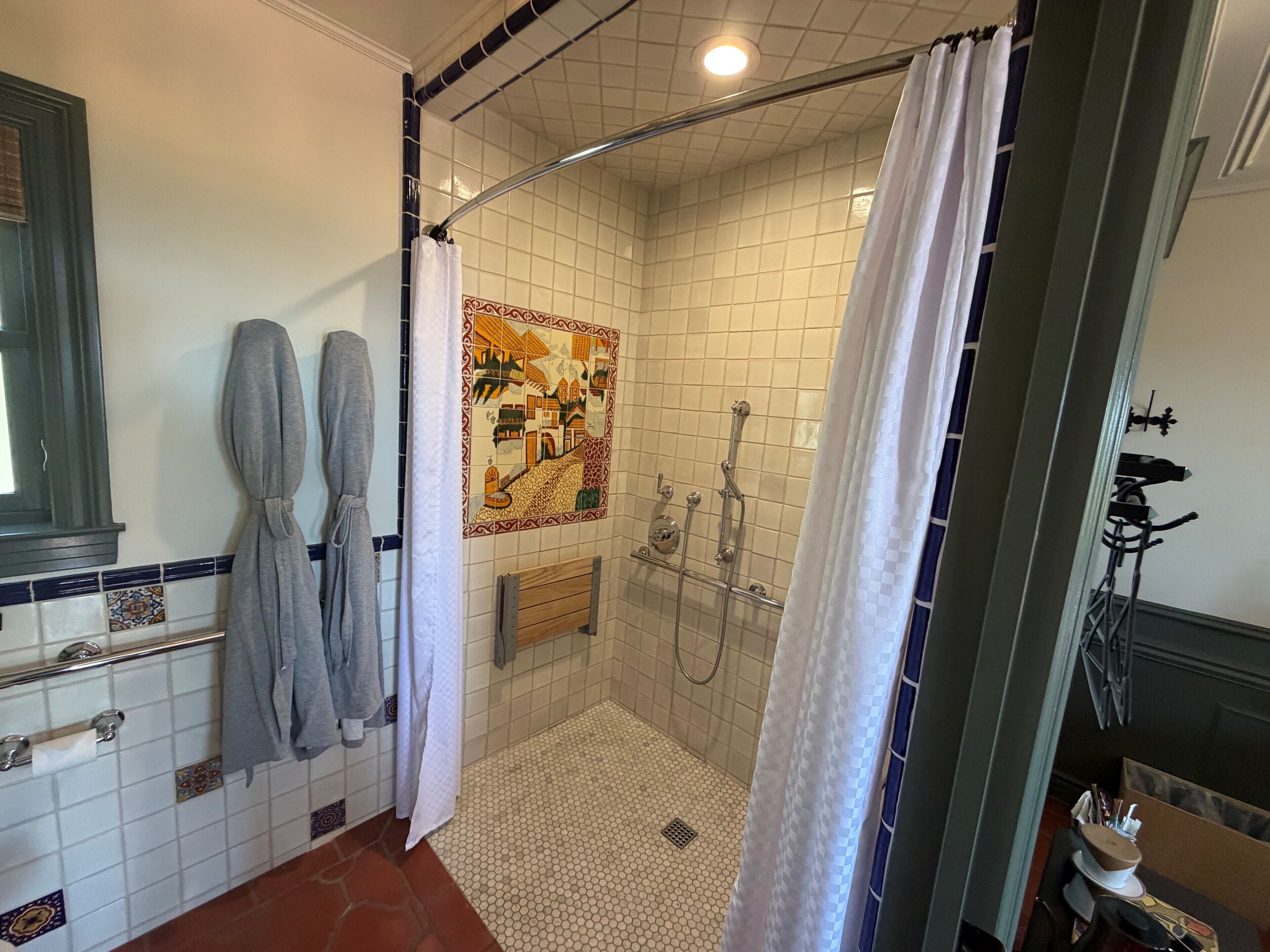 A shower with a glass door, a tiled shower area, and a towel rack with two towels.