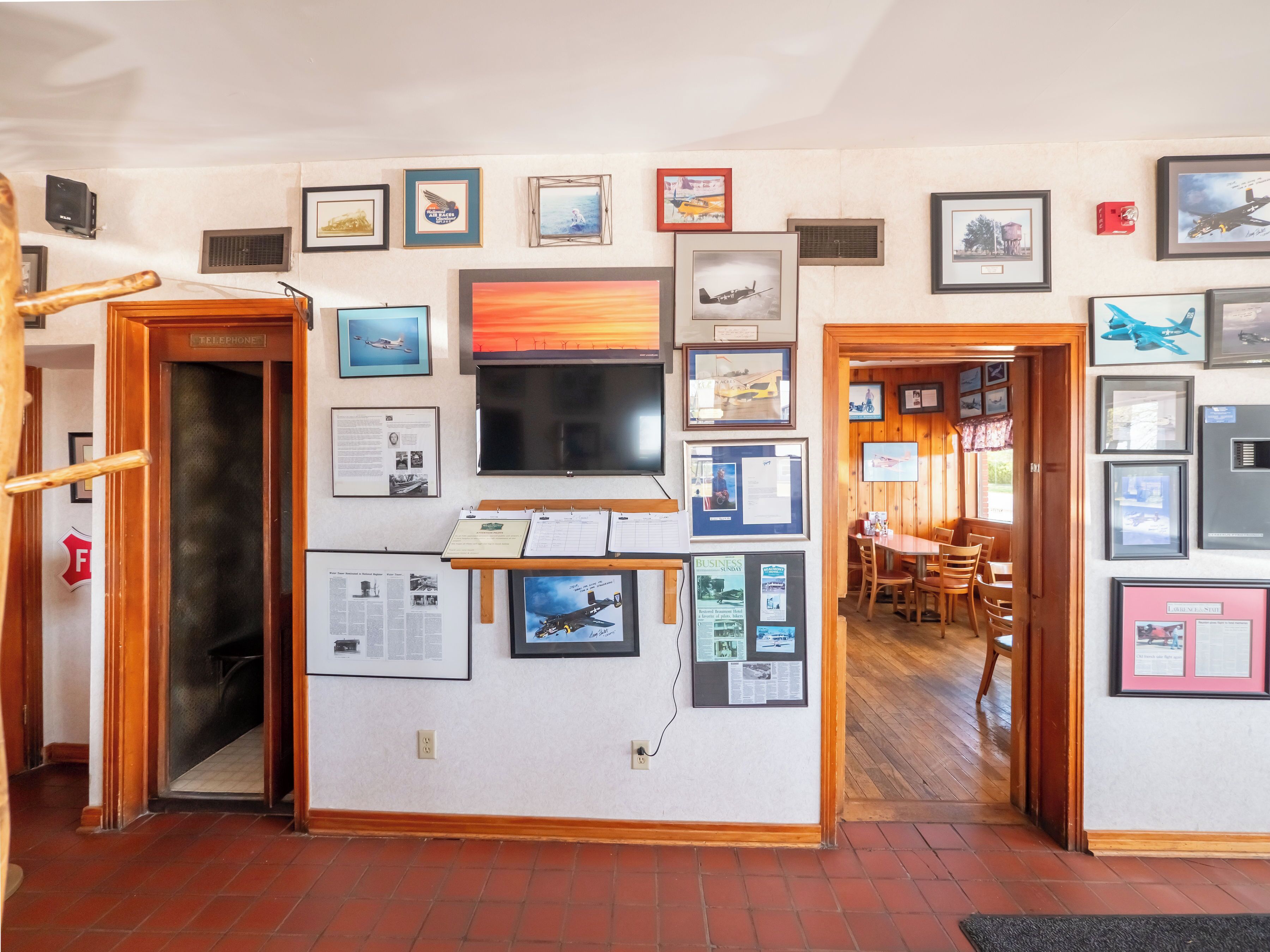 A hallway with framed pictures and a wooden door labeled "Telephone".