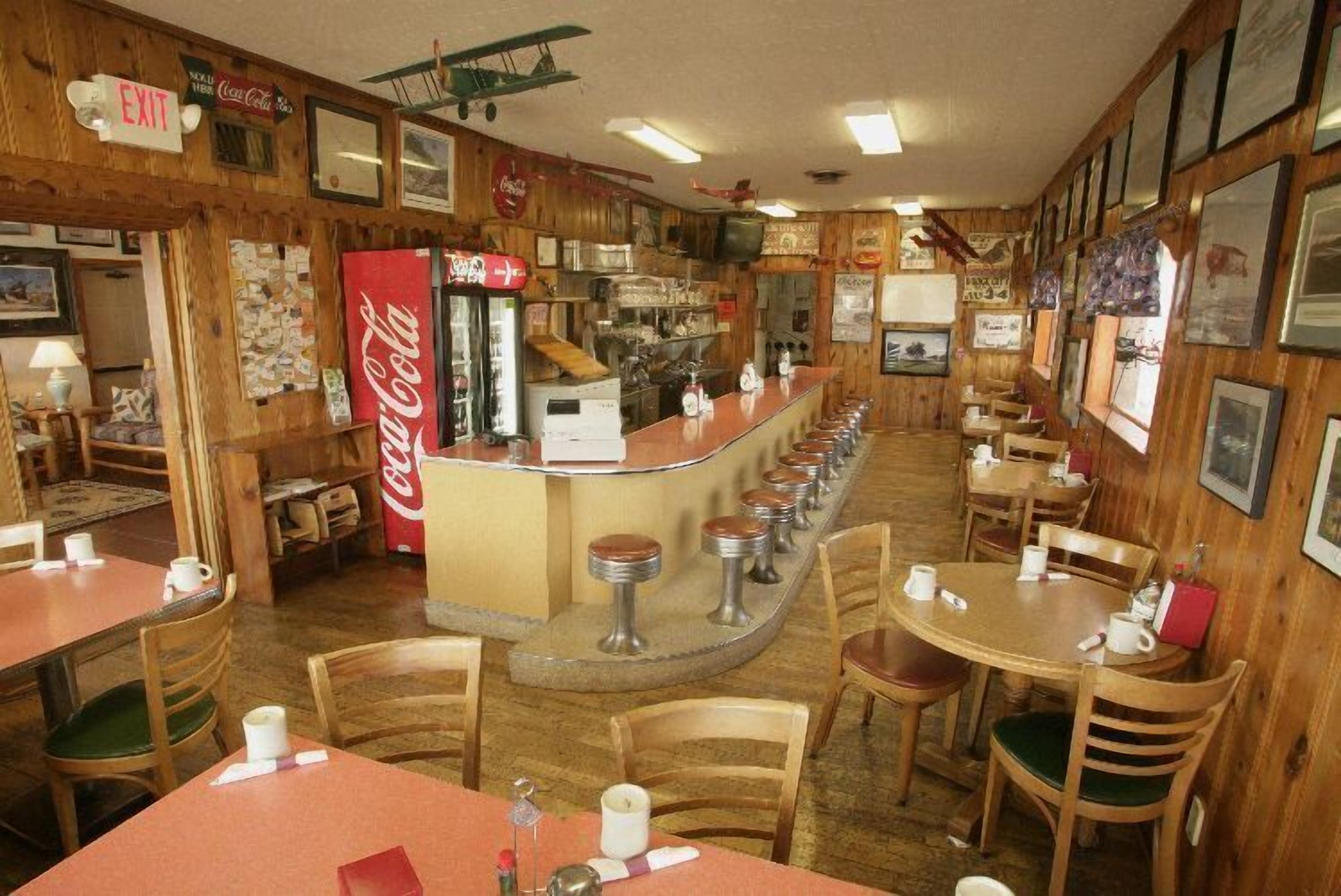 Un restaurante con decoración de madera, un refrigerador de Coca-Cola y una zona de bar.