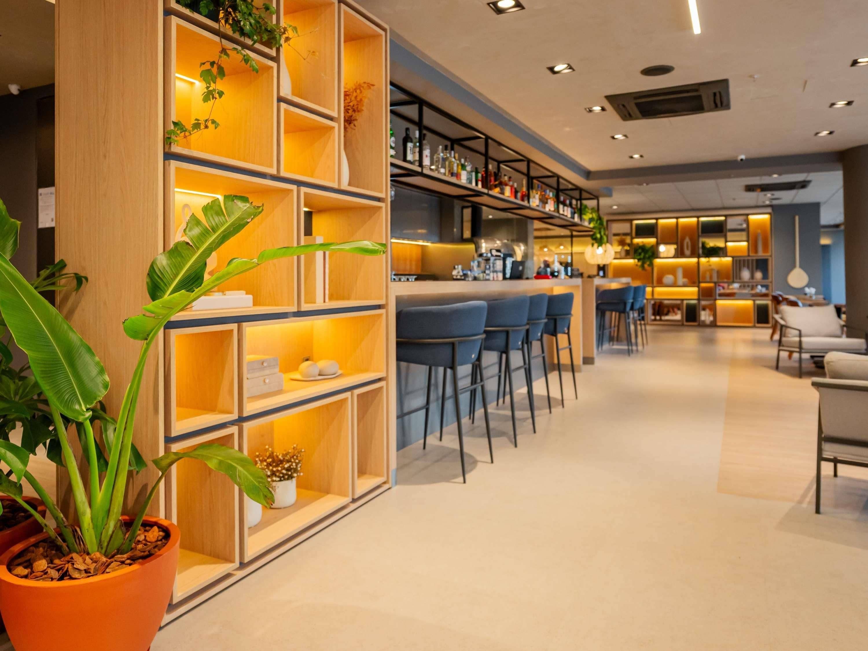 A modern bar area with wooden shelving and bar stools.