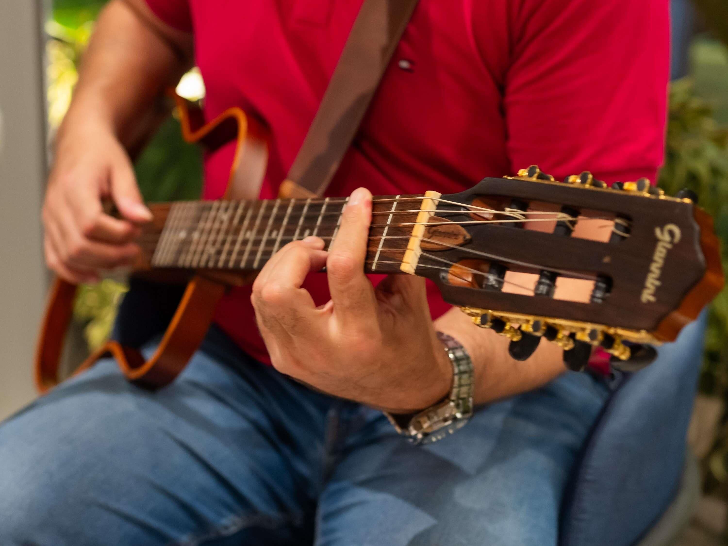 A person playing an acoustic guitar with a visible headstock and tuning pegs.