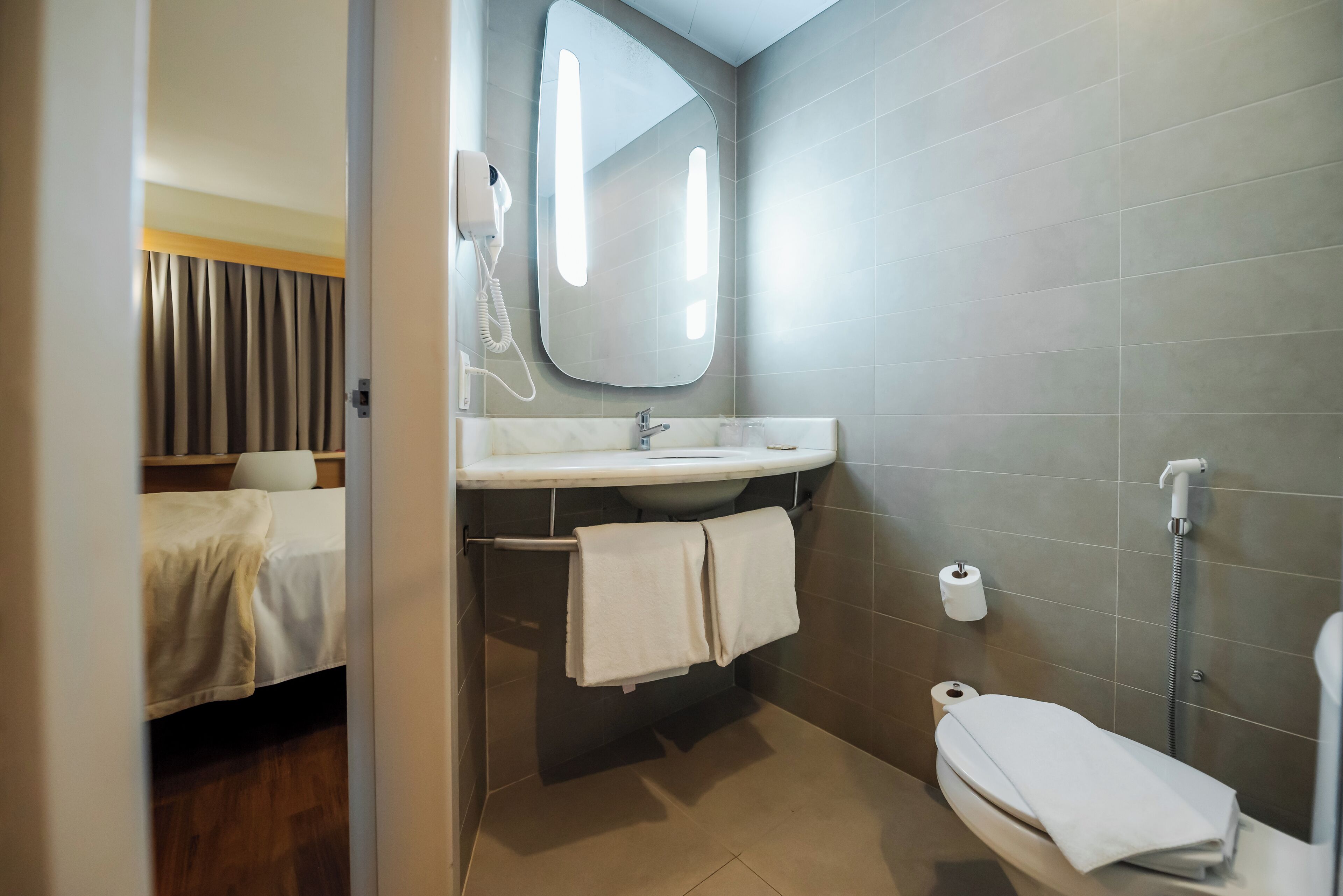Une salle de bain moderne équipée d’un lavabo, d’un miroir, d’un porte-serviettes, de toilettes et d’une douche.