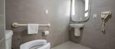 A modern bathroom with a toilet, bidet, sink, and mirror.