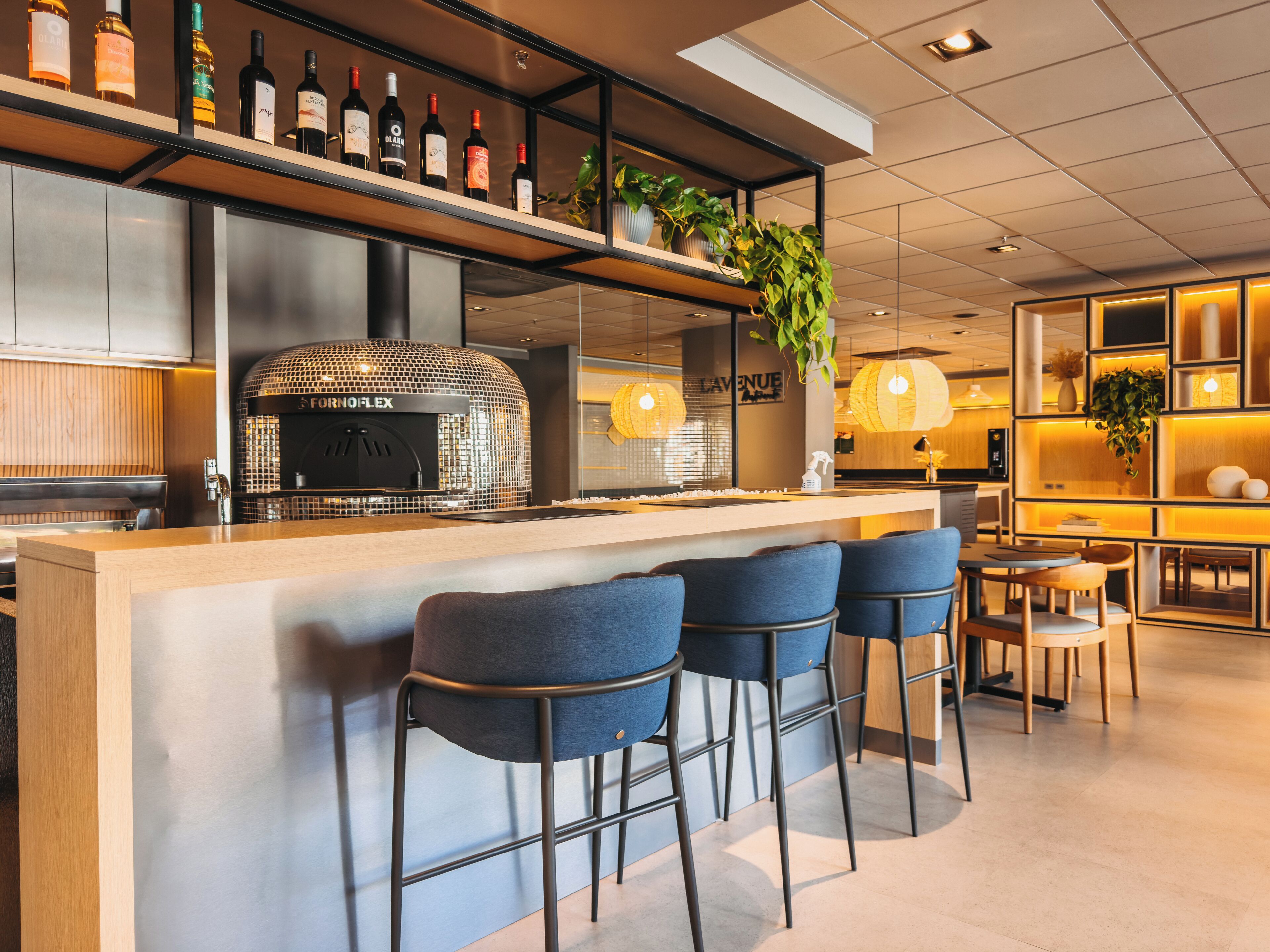 Ein moderner Barbereich mit Pizzaofen, Barhocker und Flaschenregalen.