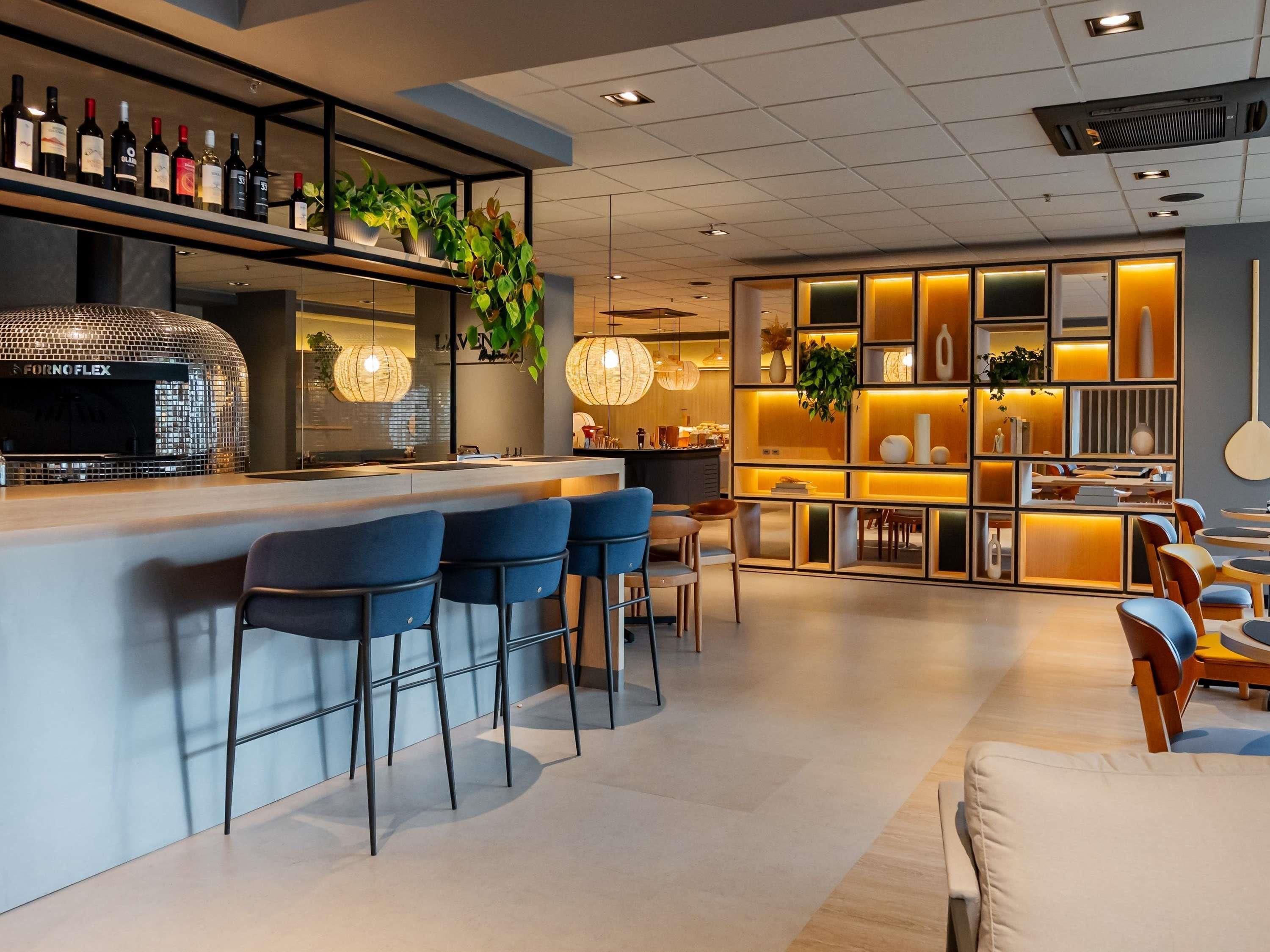 A modern bar area with a counter, bar stools, and a variety of bottles.