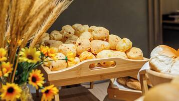 Una teca in legno esposta con diversi dolci e pane, insieme a un vaso di girasoli e spighe di grano.
