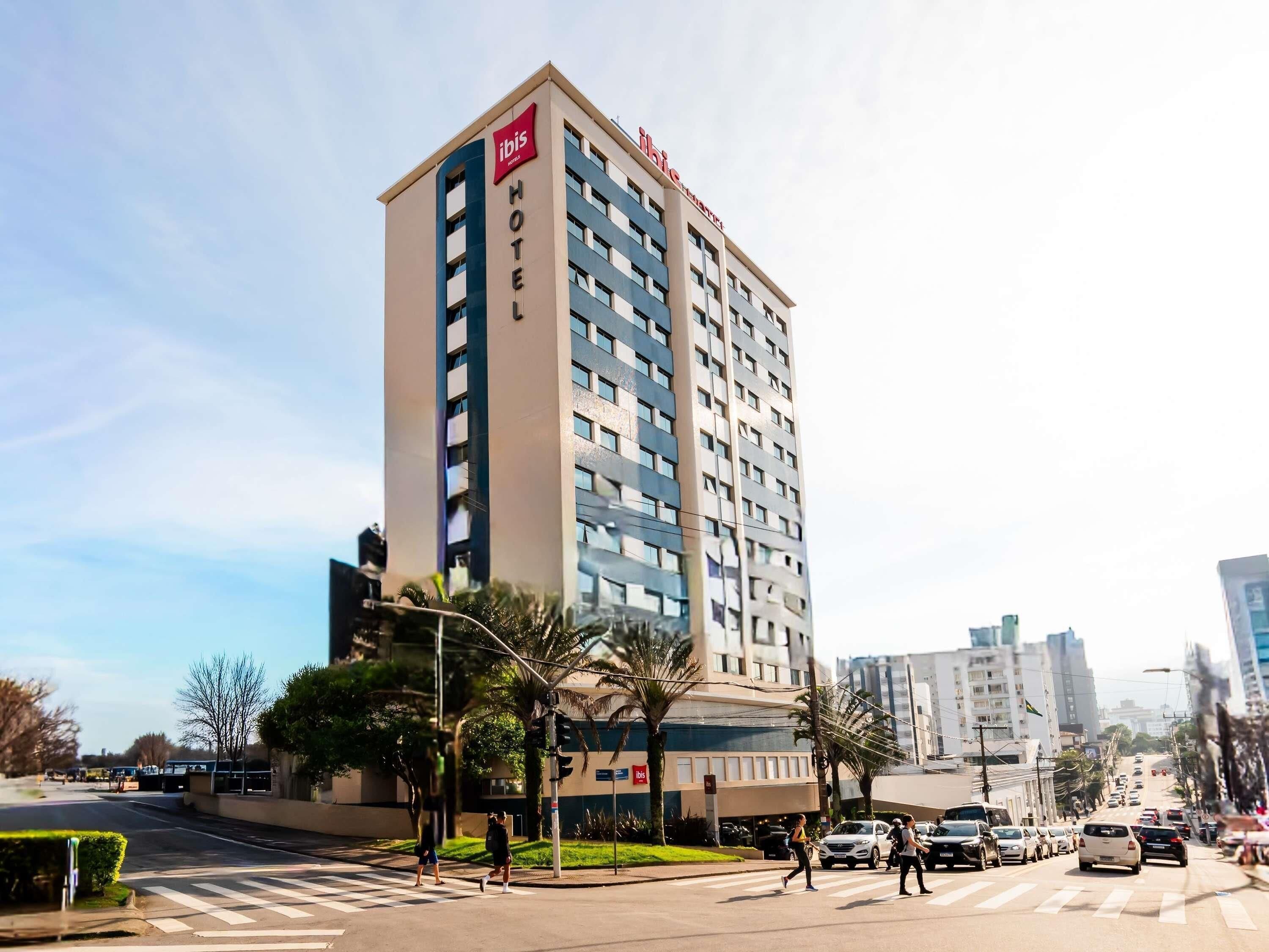Een hoog hotelgebouw met een opvallend 'ibis' logo, meerdere verdiepingen en een modern architectonisch ontwerp.