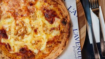 Una pizza su un tagliere di legno, con un tovagliolo e posate accanto.