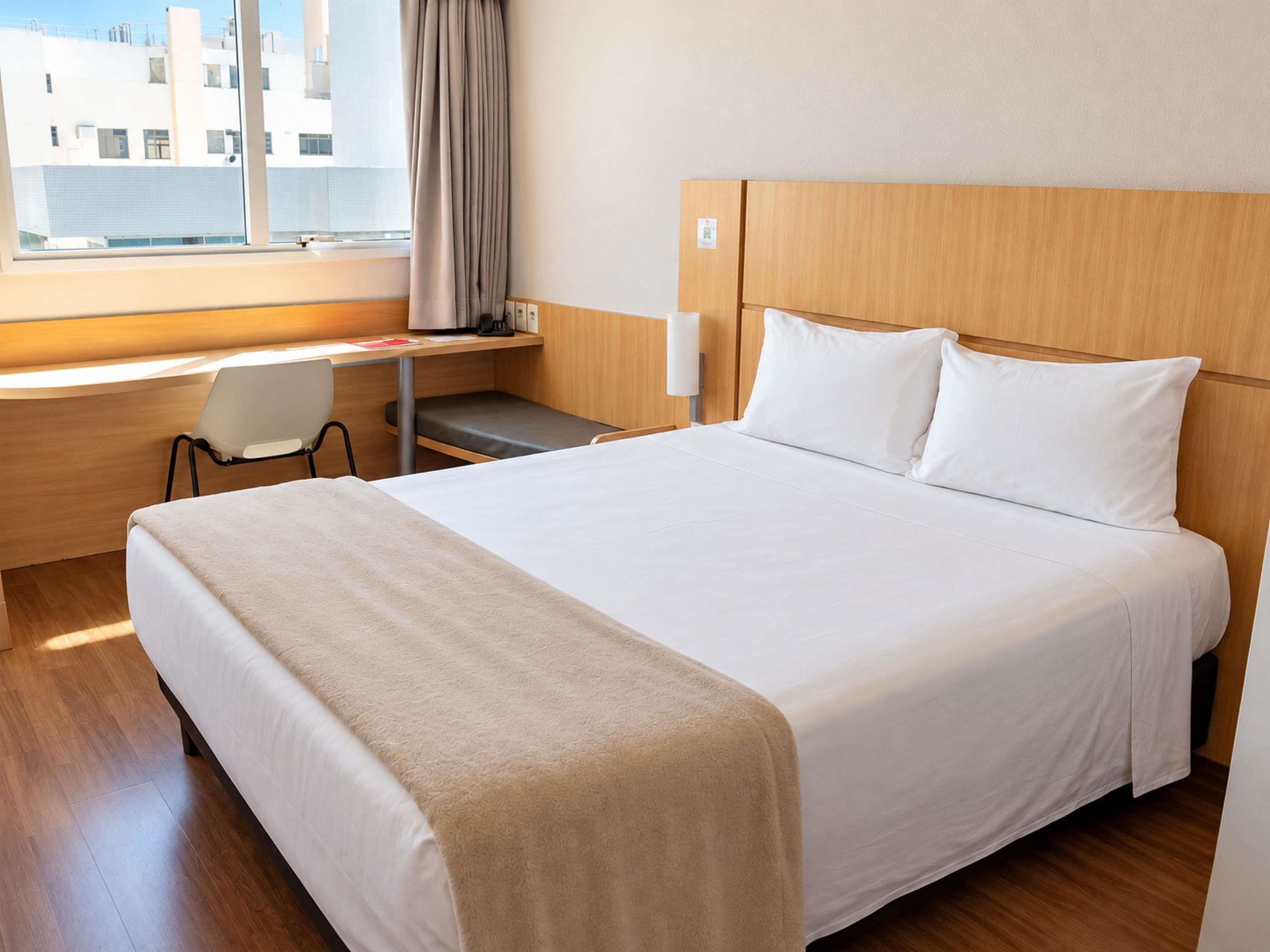 Hotellihuone, jossa on sänky, työpöytä ja tuoli.