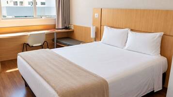 Una habitación de hotel con una cama, un escritorio y una silla.