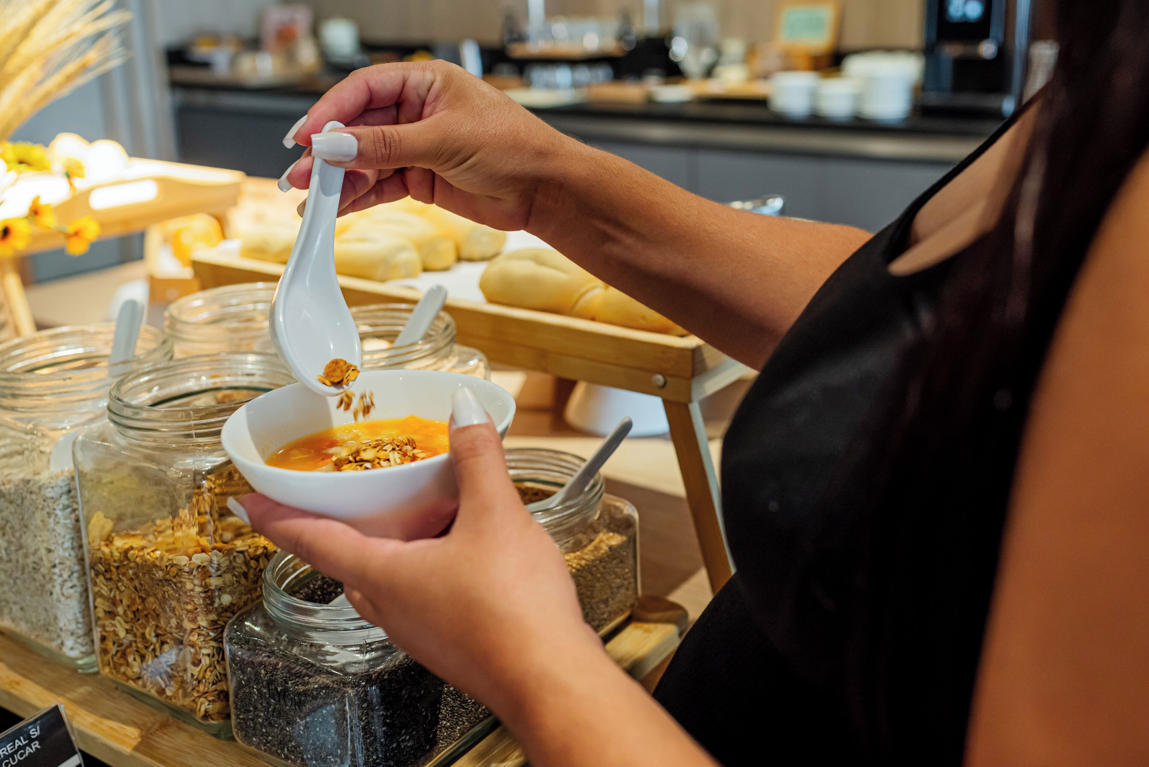 Une personne tenant un bol avec une cuillère, avec divers aliments et récipients en arrière-plan.