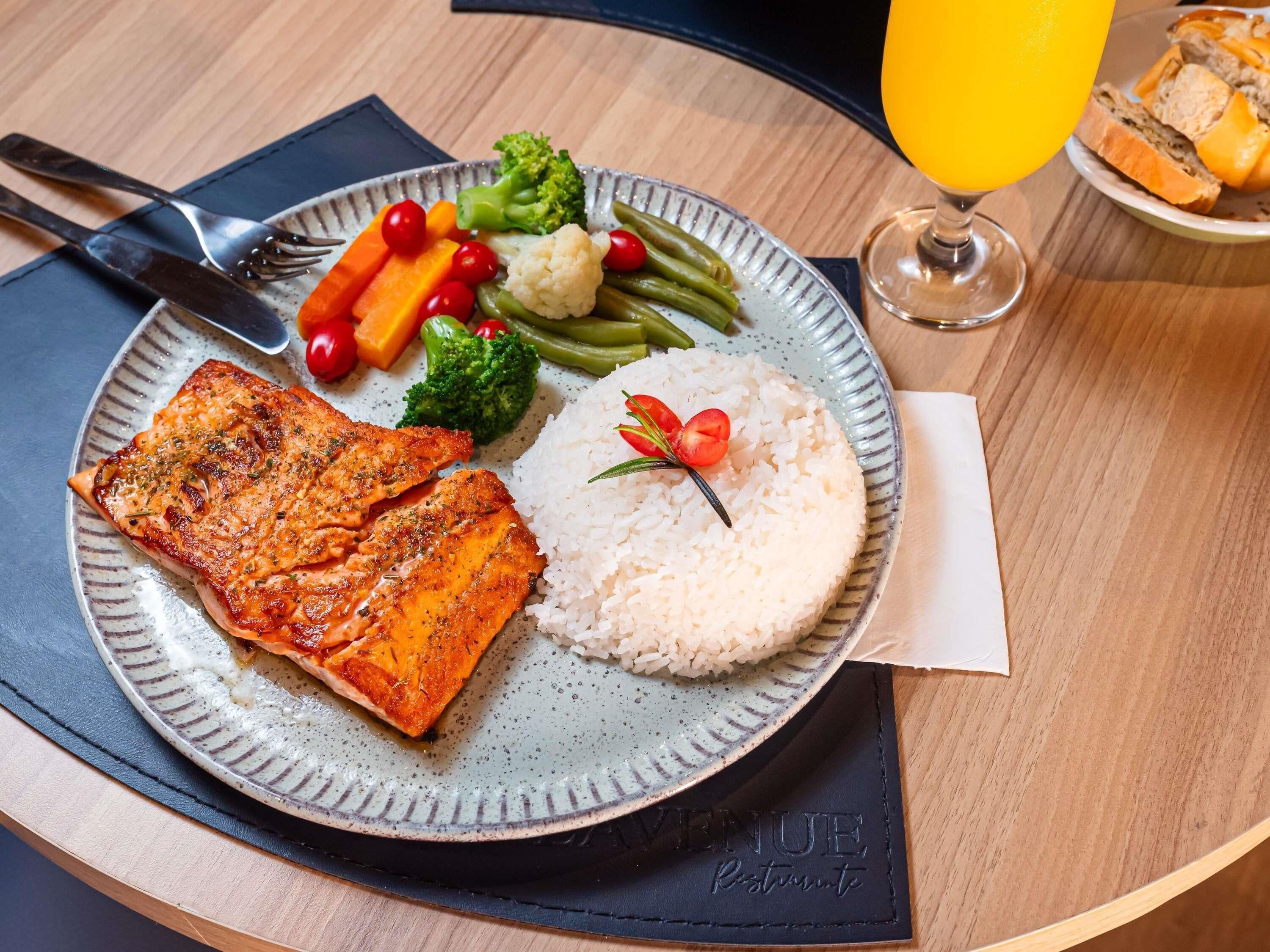 A plate with salmon, rice, and vegetables on a table.