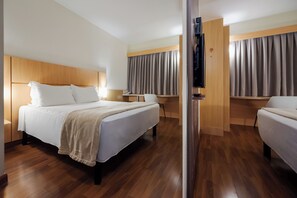 Habitación de hotel con una cama grande, una cama más pequeña, un escritorio y una zona de estar.