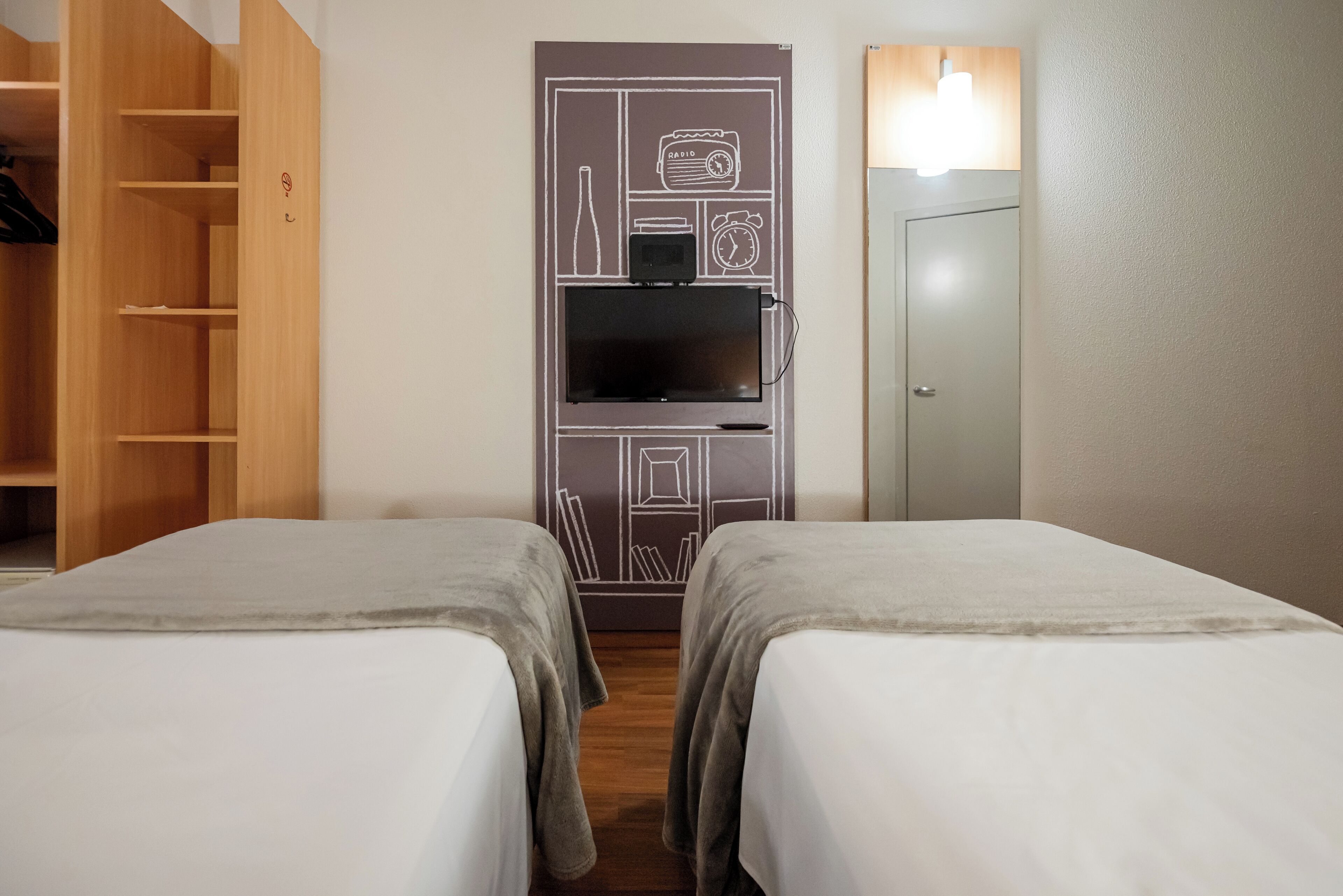 Une chambre d’hôtel avec deux lits, une armoire, une télévision et une porte.
