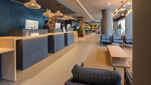 A modern hotel lobby with a reception desk, seating area, and ambient lighting.
