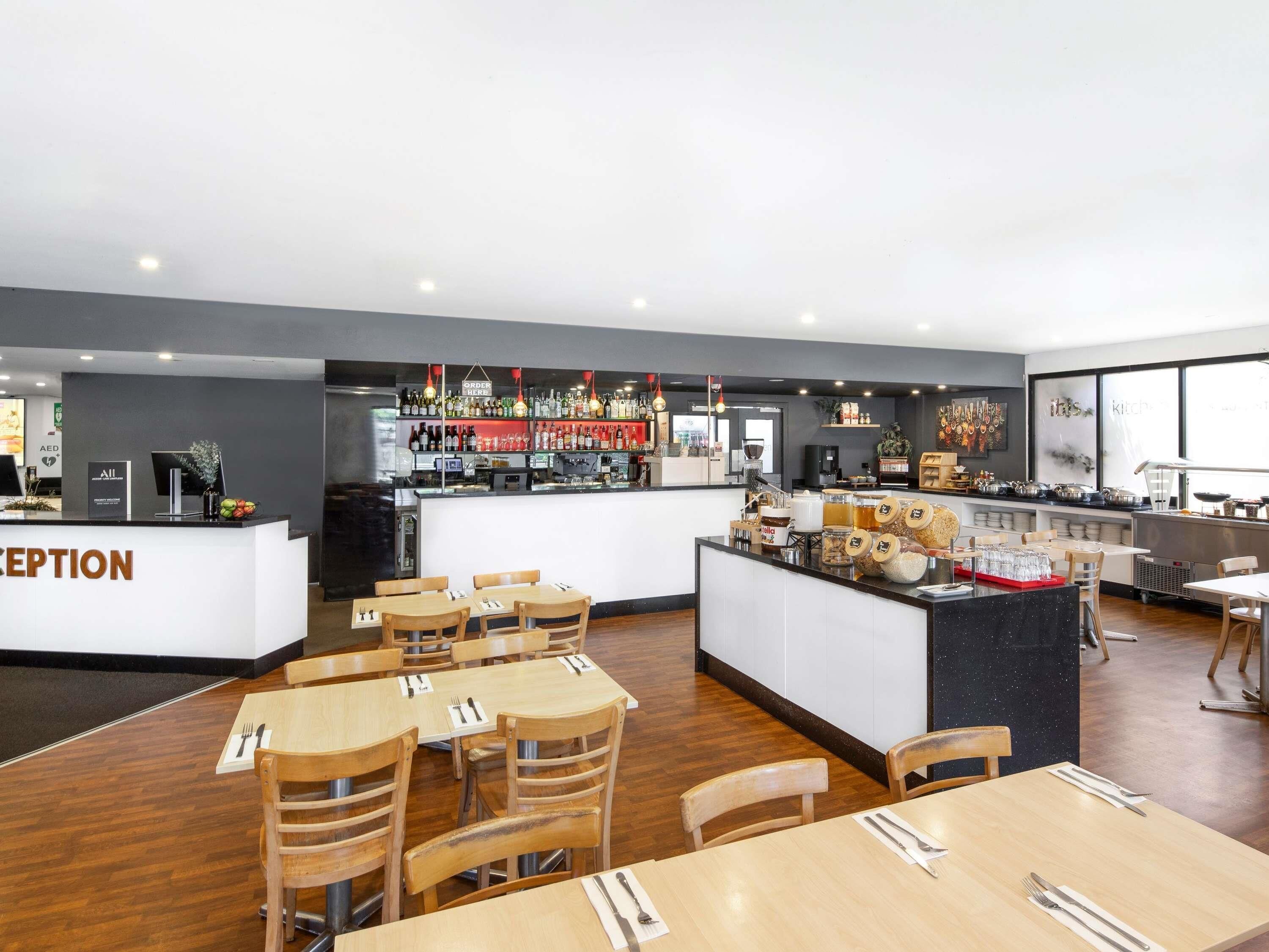 Un restaurante con una zona de recepción, mesas para comer y un bar.