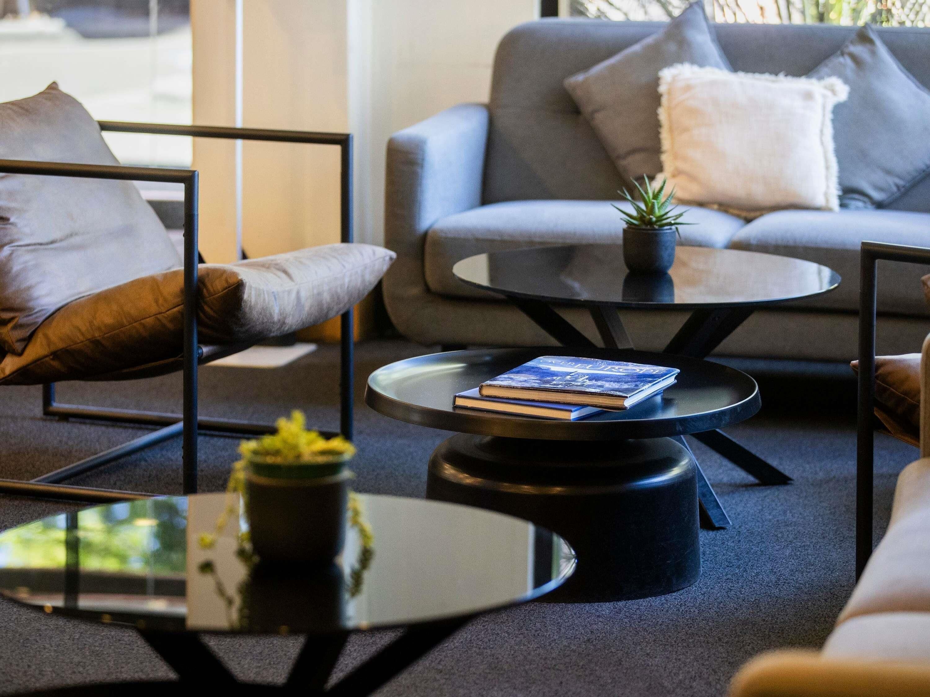 A modern living room with a grey sofa, a coffee table with a book, and a small plant.