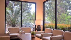 Una habitación con un gran ventanal, una mesa de madera y cuatro sillas color beige.