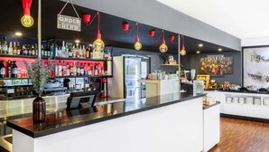 Zona de bar con mostrador, estanterías llenas de botellas y un refrigerador.