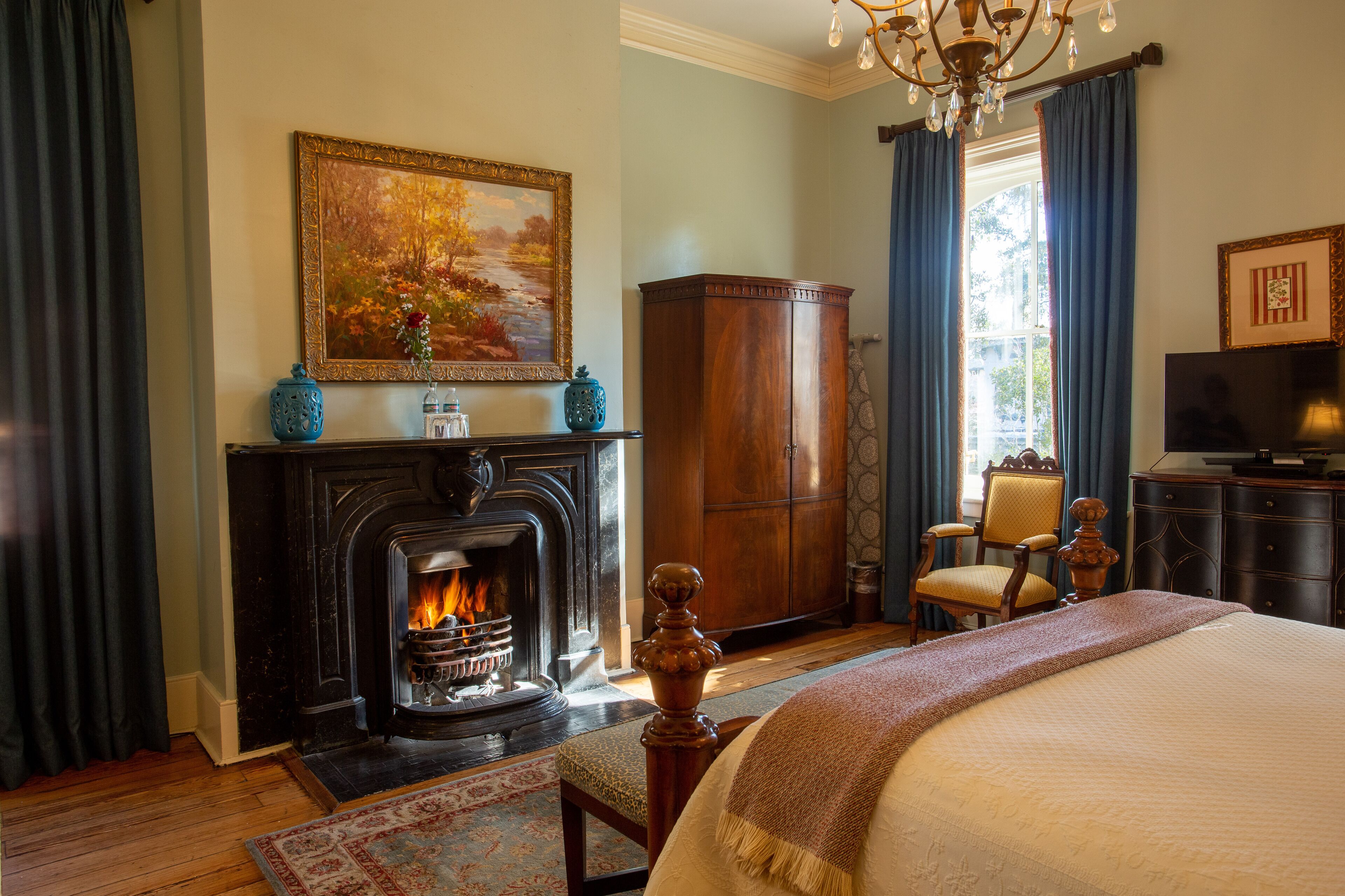 A bedroom with a fireplace, a bed, a wooden cabinet, and a television.