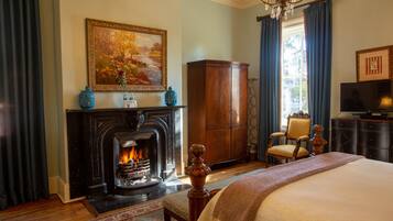 A bedroom with a fireplace, a bed, a wooden cabinet, and a television.