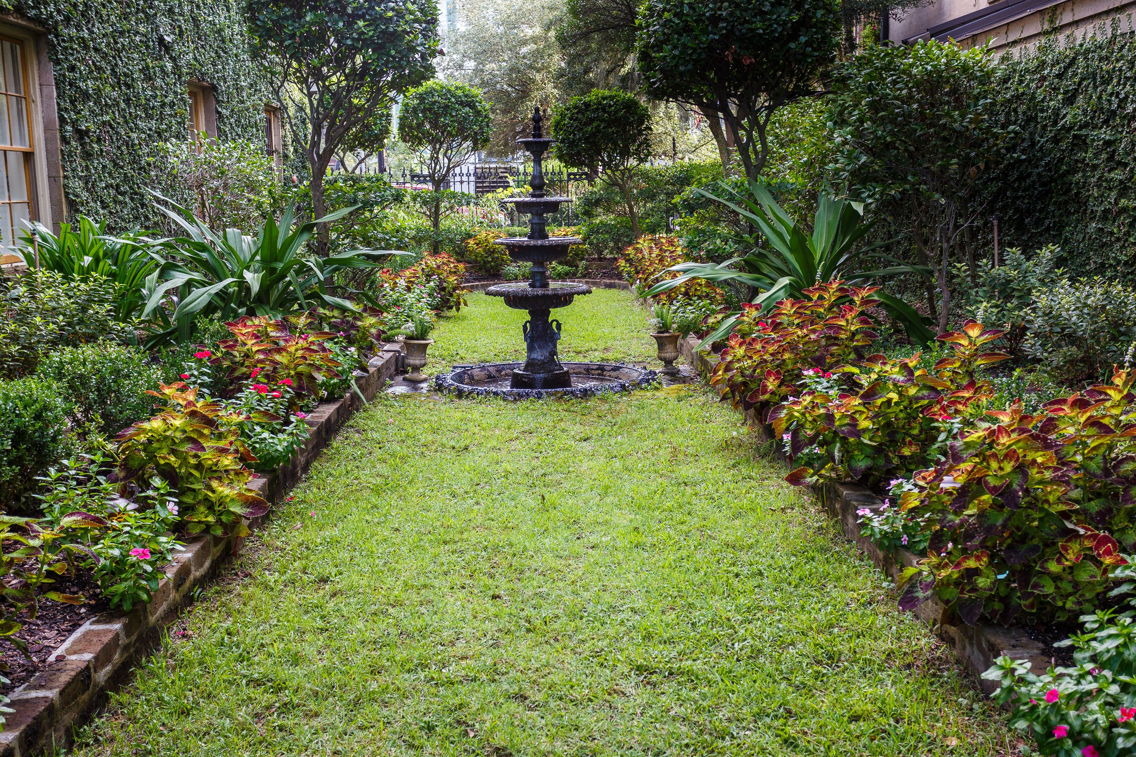 A garden with a central fountain, surrounded by well-maintained flower beds and greenery.