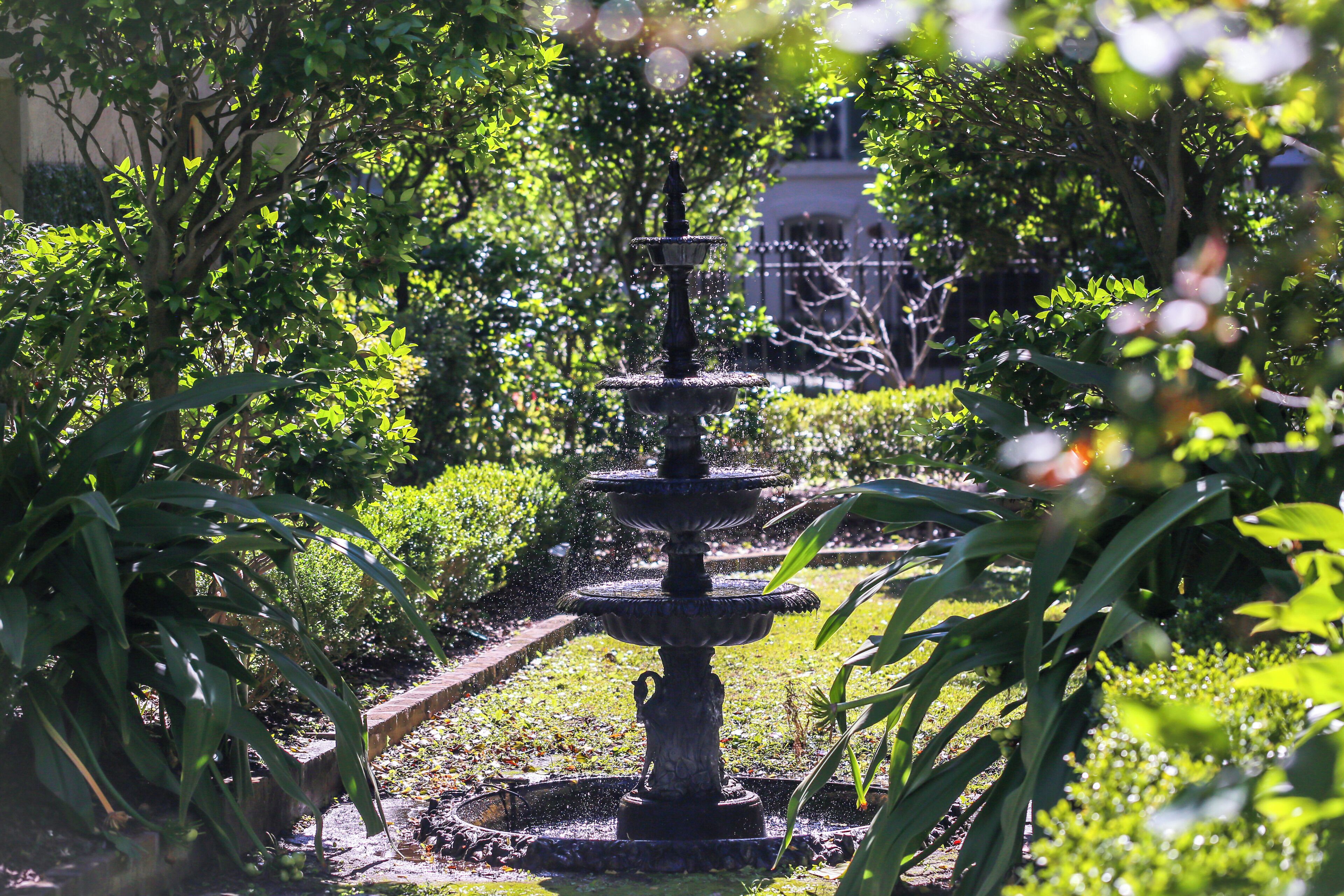 A multi-tiered fountain surrounded by lush greenery in a garden setting.