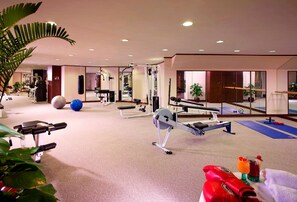 A gym with exercise equipment, a punching bag, and a blue mat. - Harbour Plaza Metropolis (Kowloon)