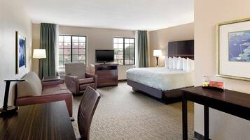 A hotel room with a bed, a desk, a chair, a television, and a window with curtains.