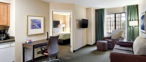 A hotel room with a desk, office chair, sofa, and a bed.