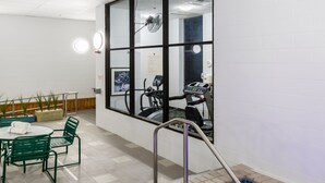 A spa area with a hot tub, exercise equipment, and a seating area with chairs and a table. - Aspen Suites (Rochester)