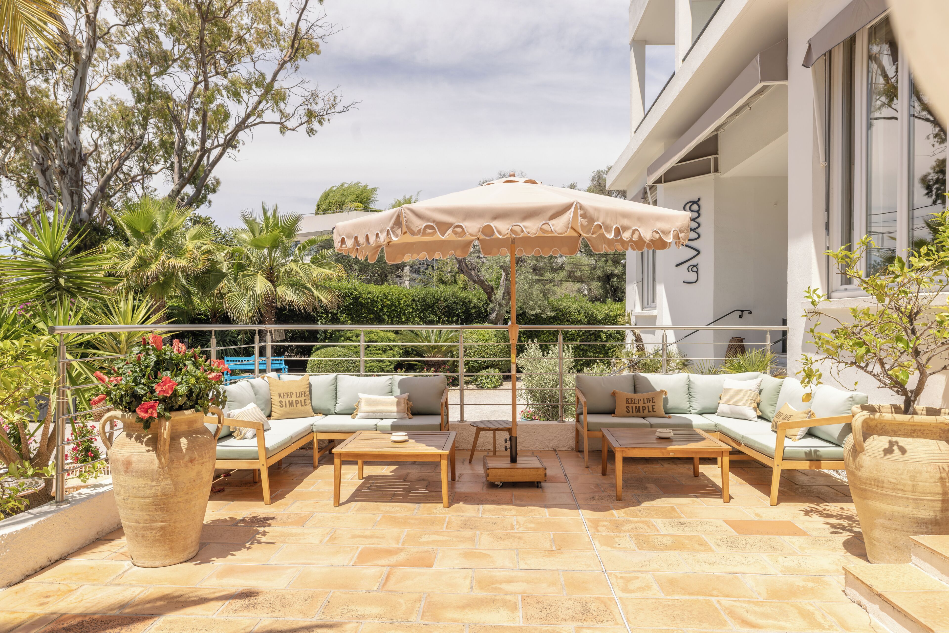 An outdoor patio with a seating area, a large umbrella, and a potted plant.