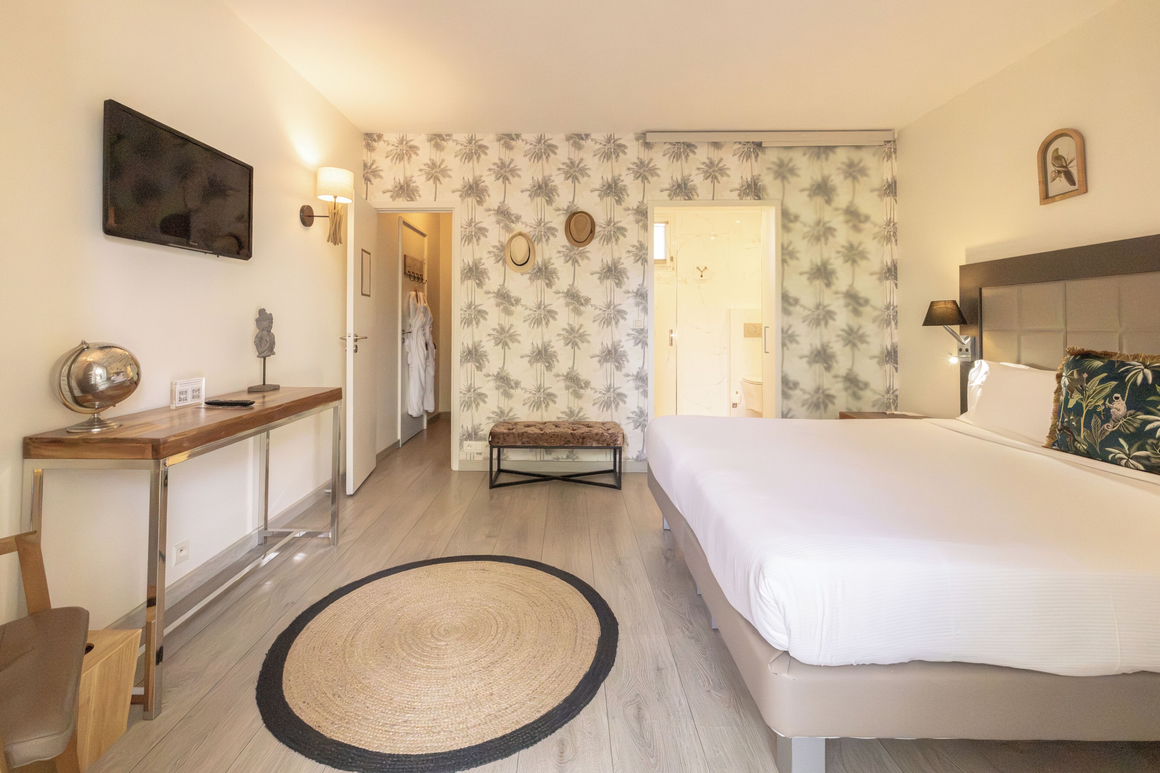 Habitación de hotel con cama, mesita de noche, lámpara y un tapete redondo.