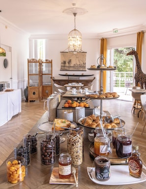 Un bufé de desayuno con diversos alimentos, una araña de cristal y una estatua de jirafa.