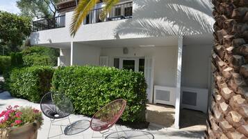 A two-story building with a balcony, a covered patio area, and a large potted plant.