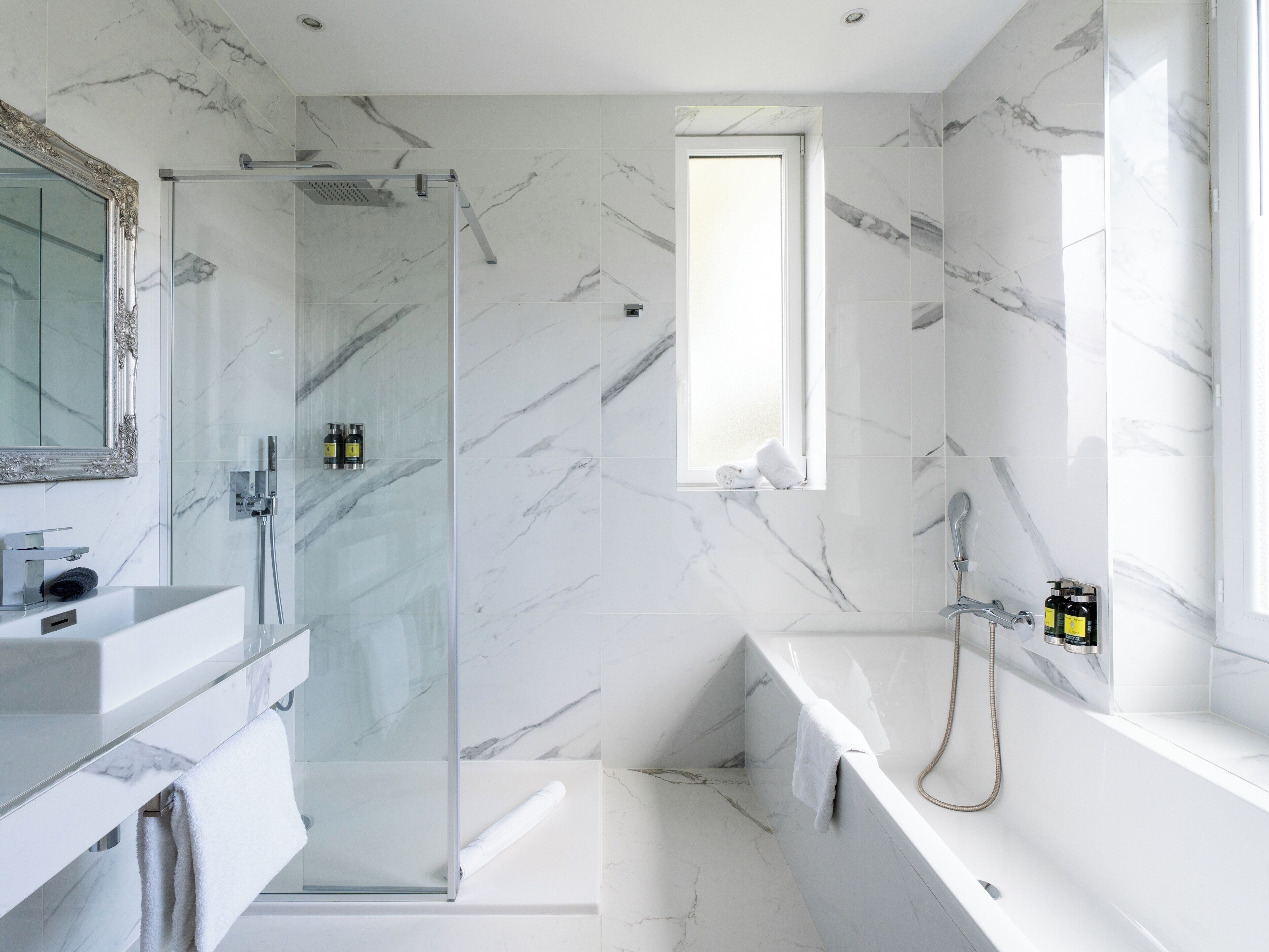 A modern bathroom with a glass shower enclosure, a bathtub, and a vanity with a mirror.