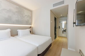 A hotel room with two beds, a large painting on the wall, a mirror, and a view into the bathroom. - Hotel Vilamari (Barcelona)