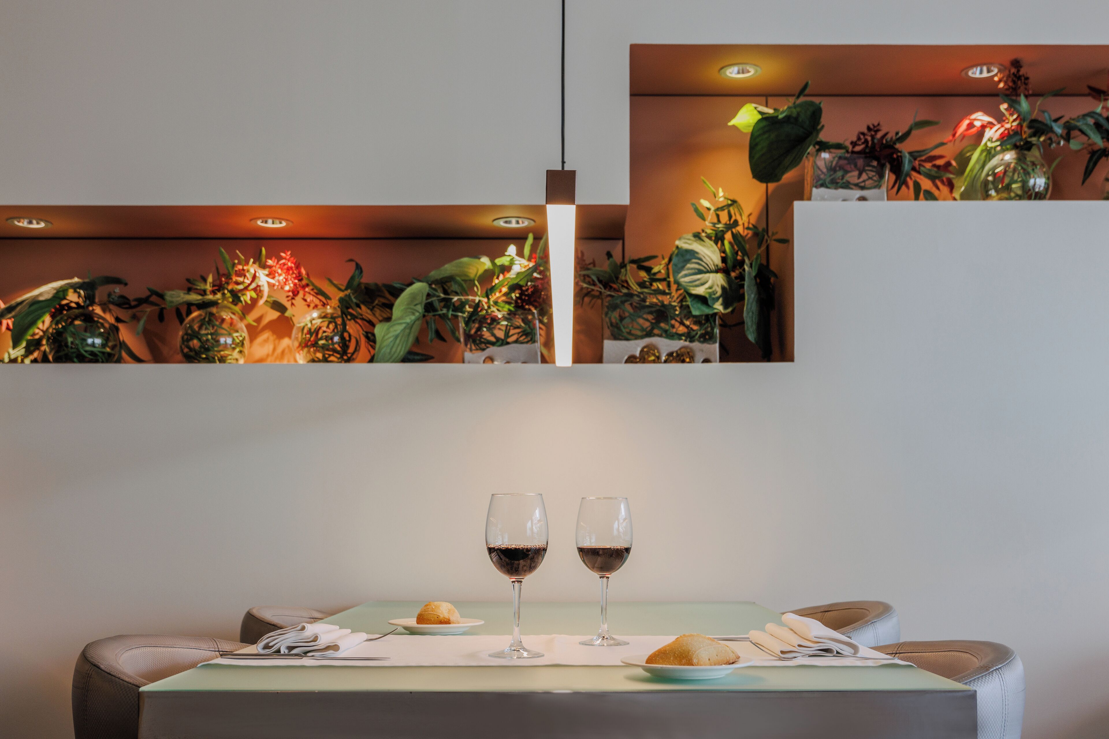 Una mesa de comedor con dos copas de vino, un plato con un pastelito y un plato pequeño con un pastel.