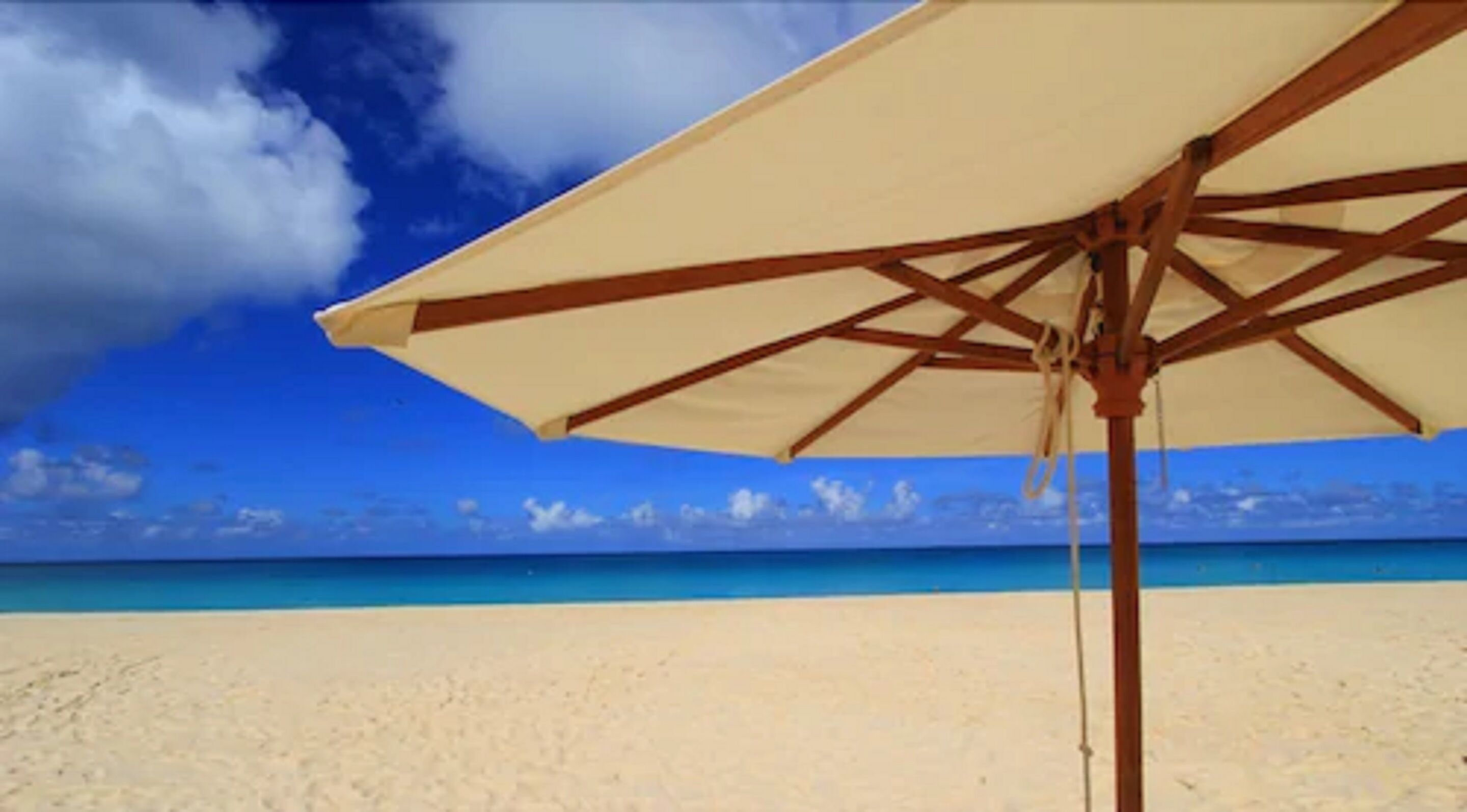 A beach umbrella with a clear view of the ocean and sky.