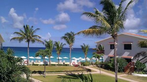 A resort with a pool area, palm trees, and a view of the ocean. - Carimar Beach Club (West End Village)
