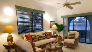 A living room with a sofa, two armchairs, a coffee table, a floor lamp, and a ceiling fan. - Carimar Beach Club (West End Village)