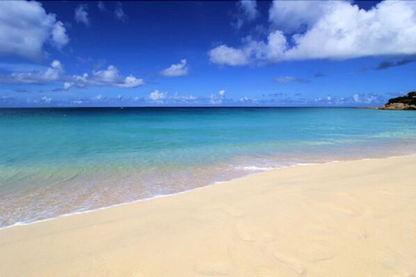 Di pantai, pasir putih, kursi berjemur, dan payung pantai