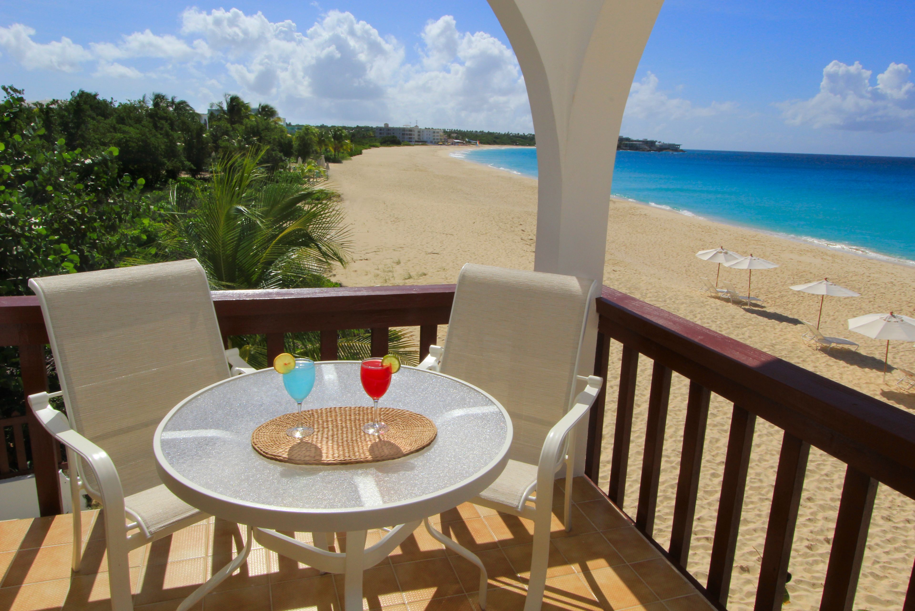 Un balcón con mesa y sillas con vista a la playa.