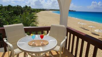 Un balcón con mesa y sillas con vista a la playa.