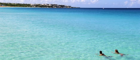 En la playa, playa de arena blanca, camastros y sombrillas 