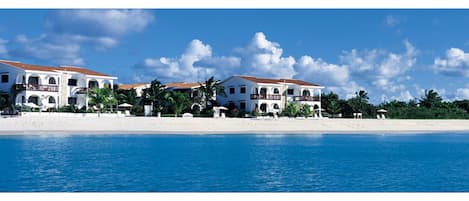 Di pantai, pasir putih, kursi berjemur, dan payung pantai